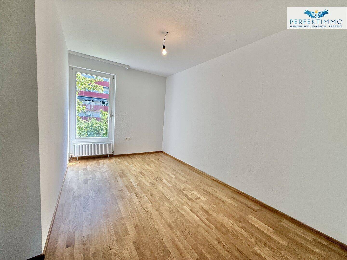 Helles Zimmer mit Parkettboden und Fenster, ideal als Schlaf- oder Arbeitszimmer.