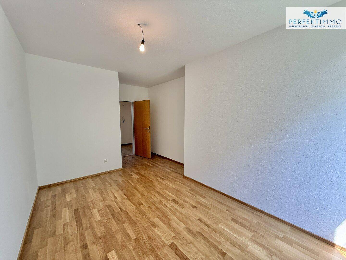 Geräumiges Zimmer mit Parkettboden und Zugang zu anderen Bereichen der Wohnung.