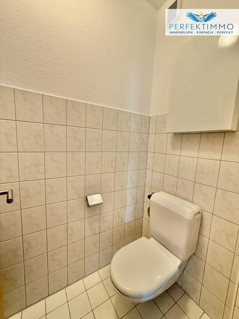 Kleines, gefliestes WC mit Toilette und einfacher Ausstattung.