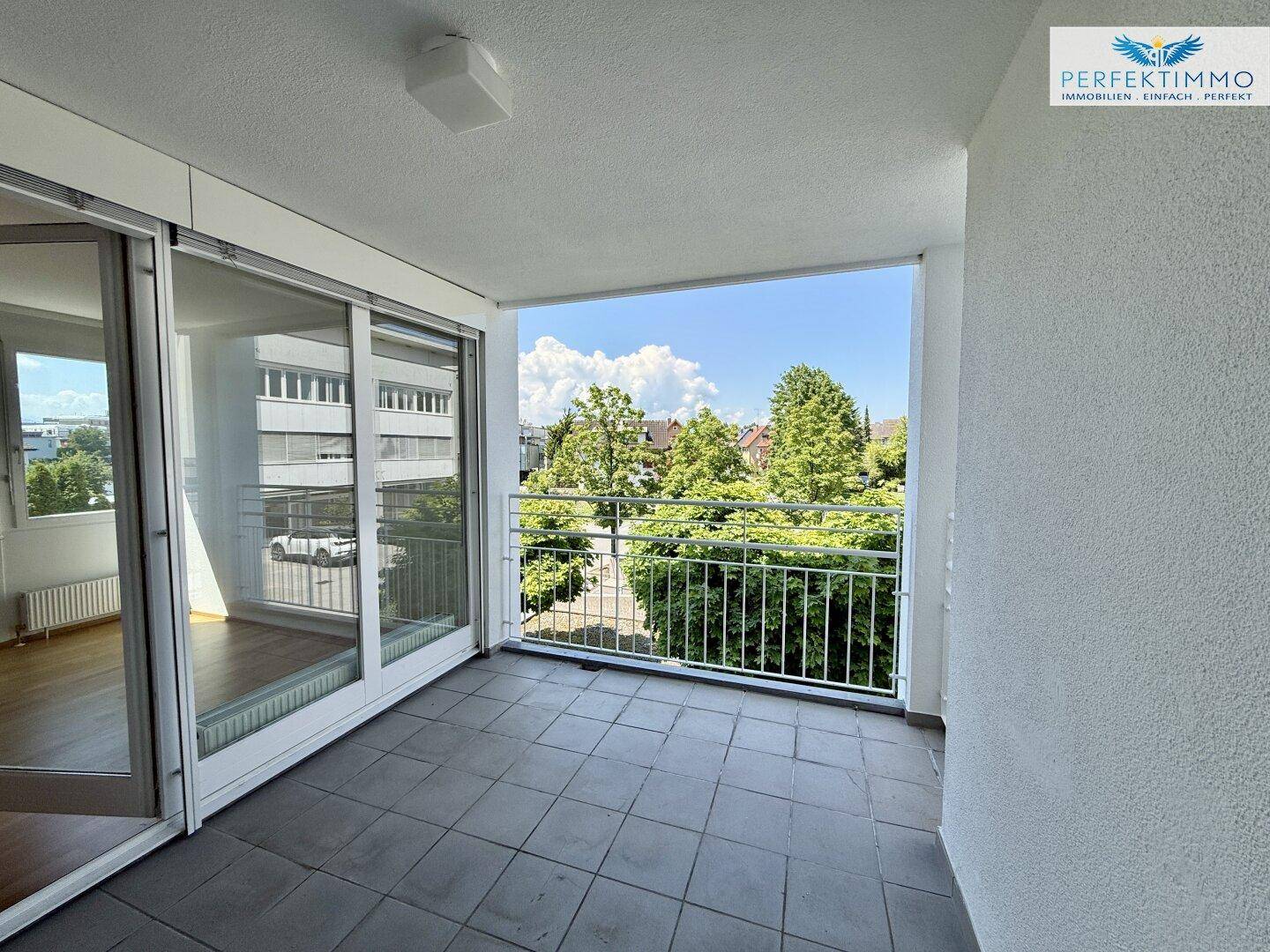Geräumiger Balkon mit Fliesenboden und schöner Aussicht auf Bäume und die Umgebung.