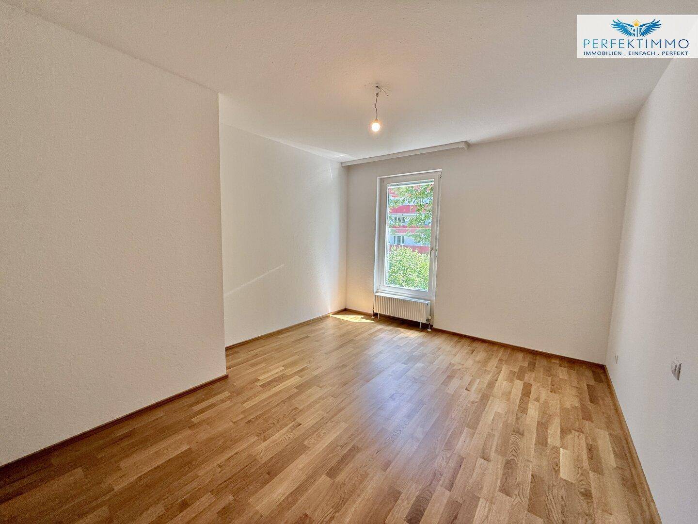 Geräumiges Schlafzimmer mit Parkettboden und weiß gestrichenen Wänden.