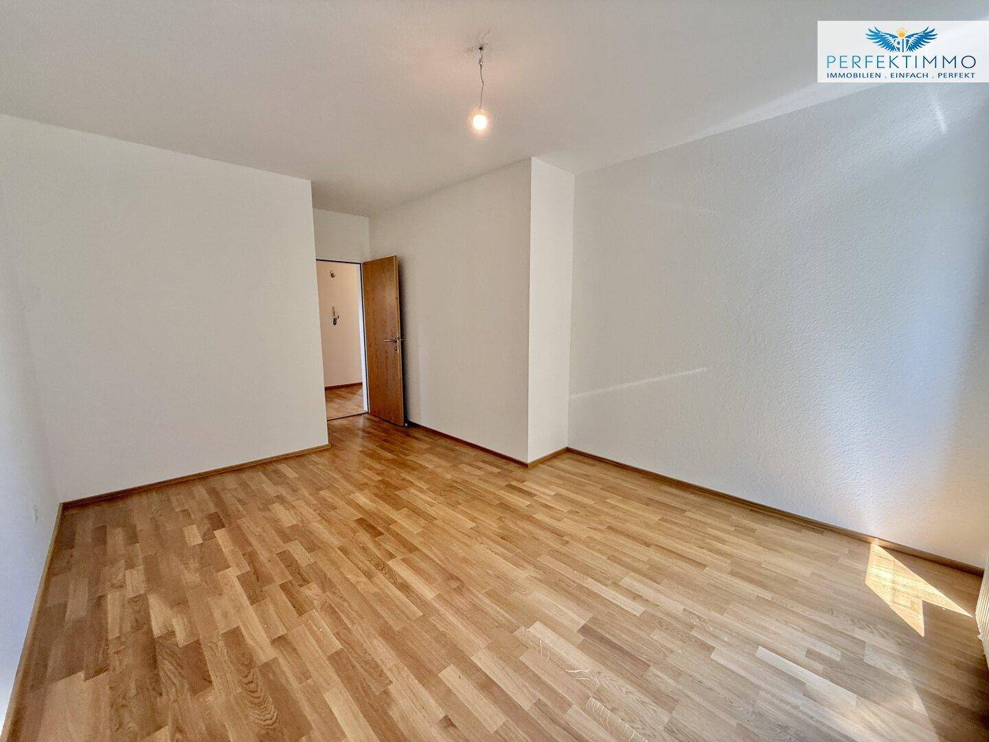 Schlafzimmer mit Holzboden und Zugang zu einem weiteren Raum.