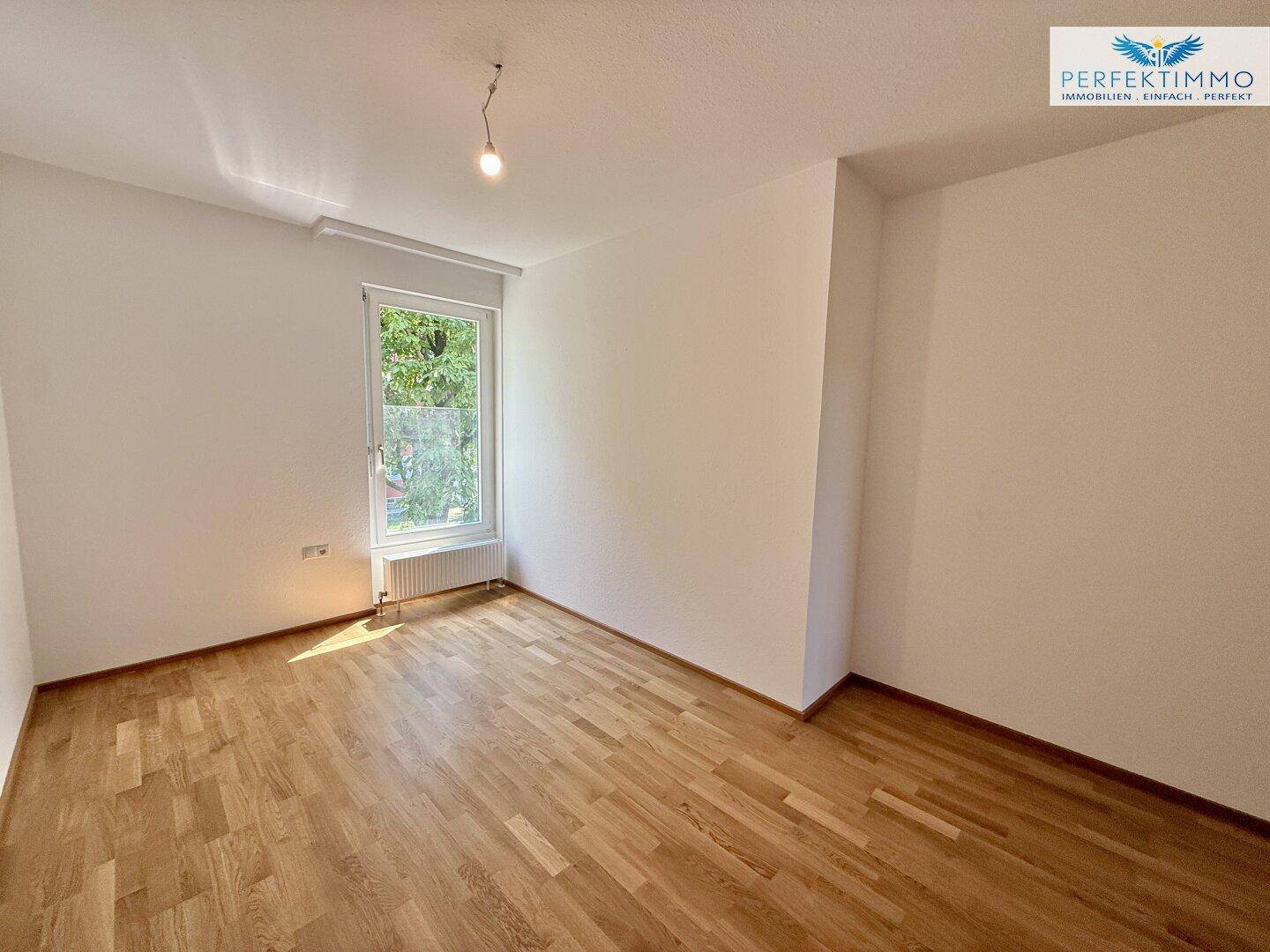 Geräumiges Zimmer mit Parkettboden und viel natürlichem Licht durch das Fenster.
