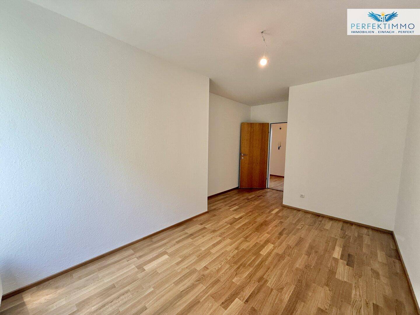 Schlafzimmer mit Holzboden und weiß gestrichenen Wänden, bereit zur individuellen Gestaltung.