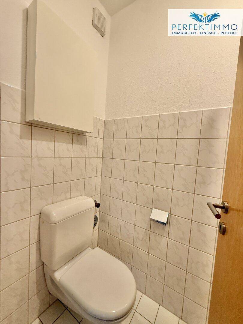 Kleines, gefliestes WC mit Toilette und einfacher Ausstattung.