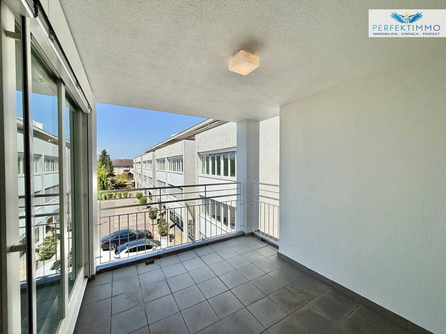 Heller Balkon mit Fliesenboden und Metallgeländer, bietet einen weiten Blick auf die Umgebung.