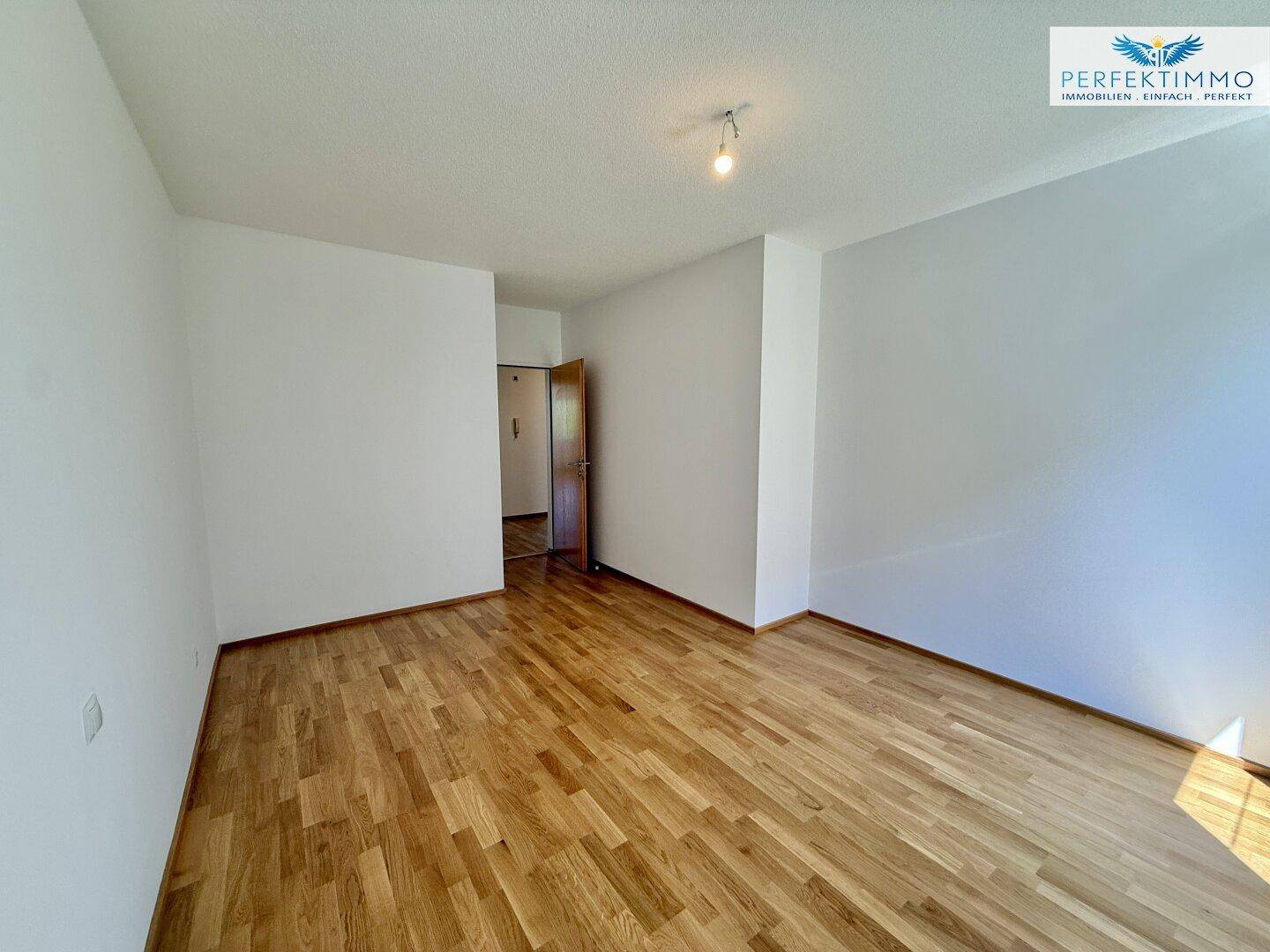 Helles Schlafzimmer mit Parkettboden und Zugang zum Flur, in einem gepflegten Zustand.