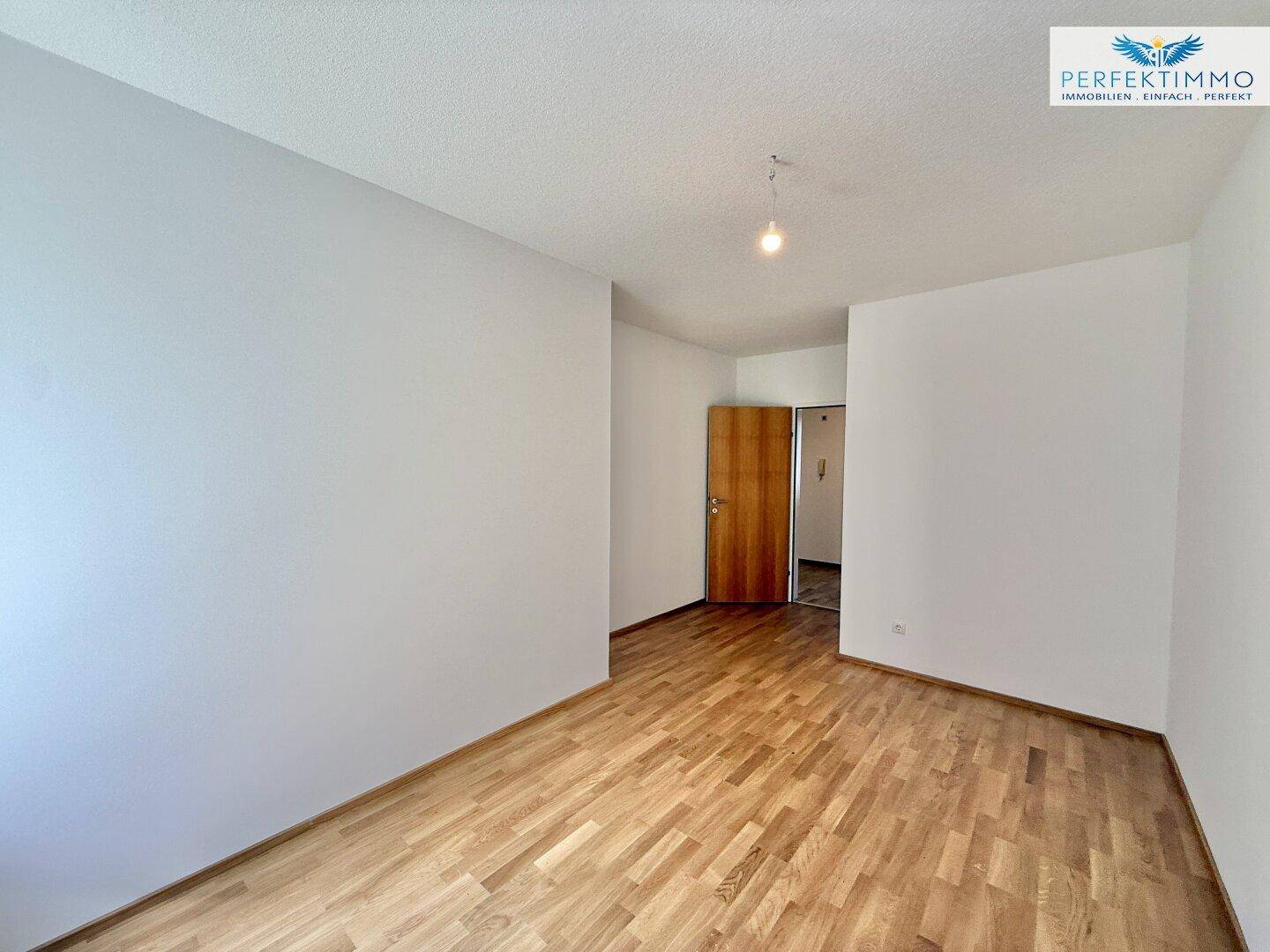 Helles Schlafzimmer mit Parkettboden und Zugang zum Flur, in einem gepflegten Zustand.
