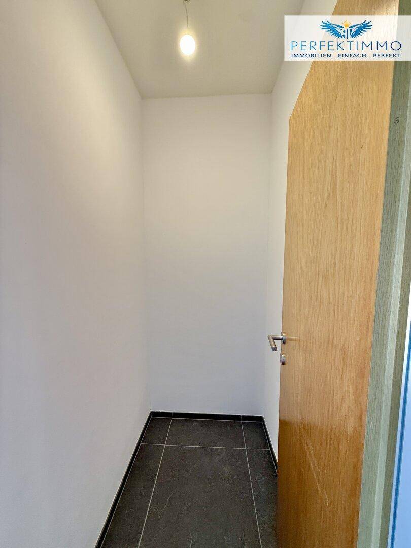 Kleiner Abstellraum mit Fliesenboden und einer Holztür, ideal für zusätzlichen Stauraum.