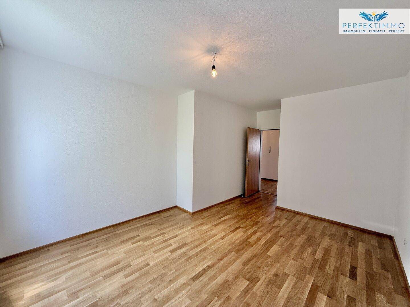Geräumiges Schlafzimmer mit Parkettboden und Zugang zum Flur.