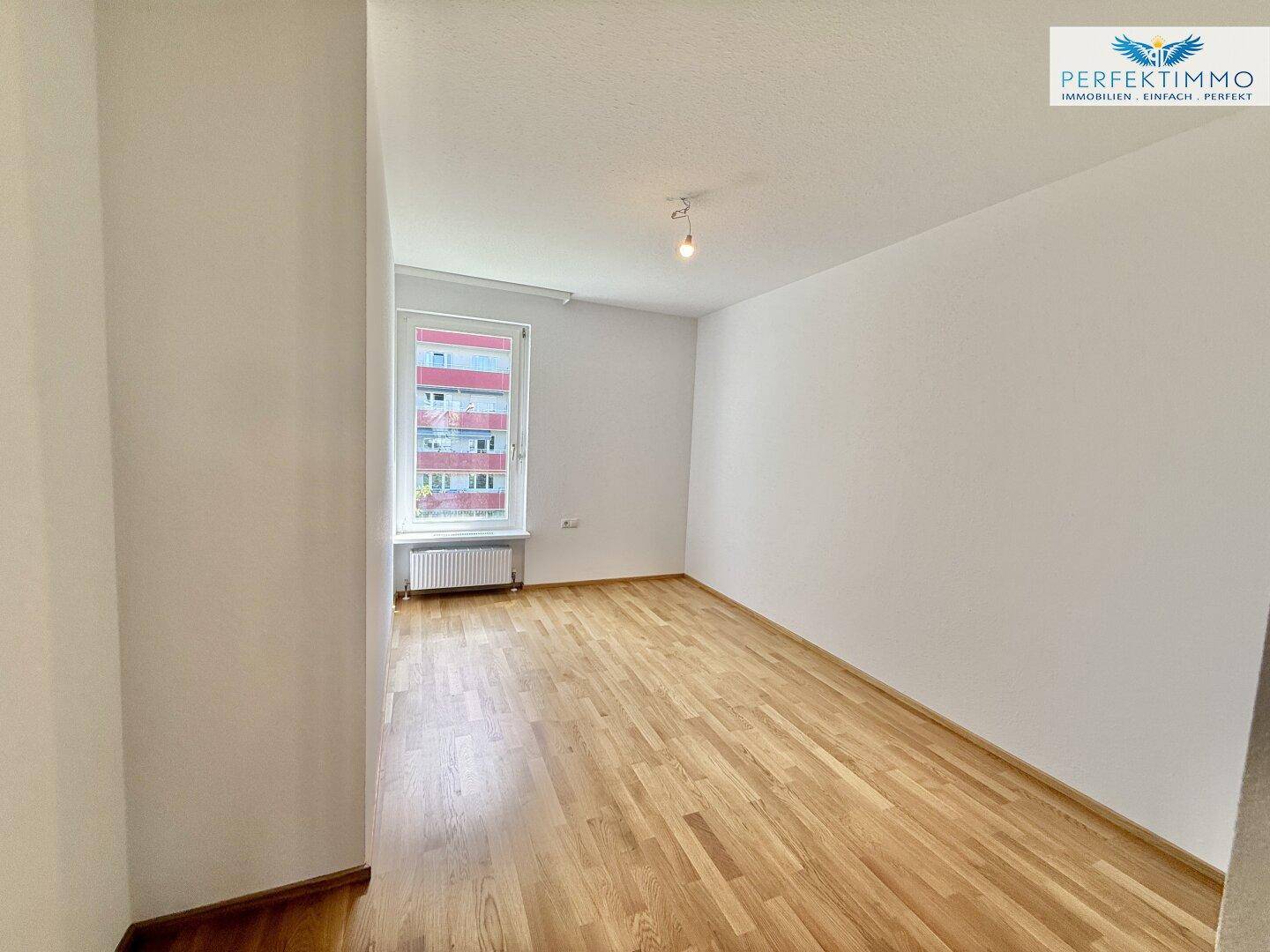 Schlafzimmer mit Parkettboden, Fenster und ausreichend Platz für Möbel.