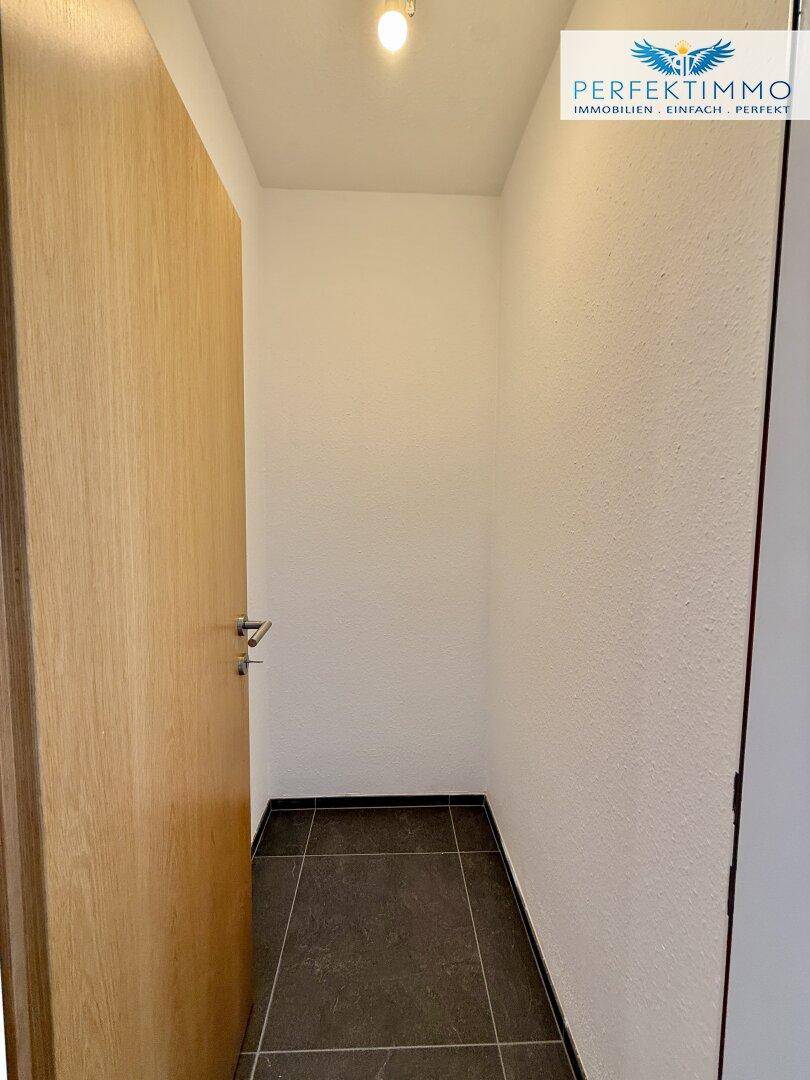 Kleiner Abstellraum oder Nische mit Fliesenboden und weiß gestrichenen Wänden.