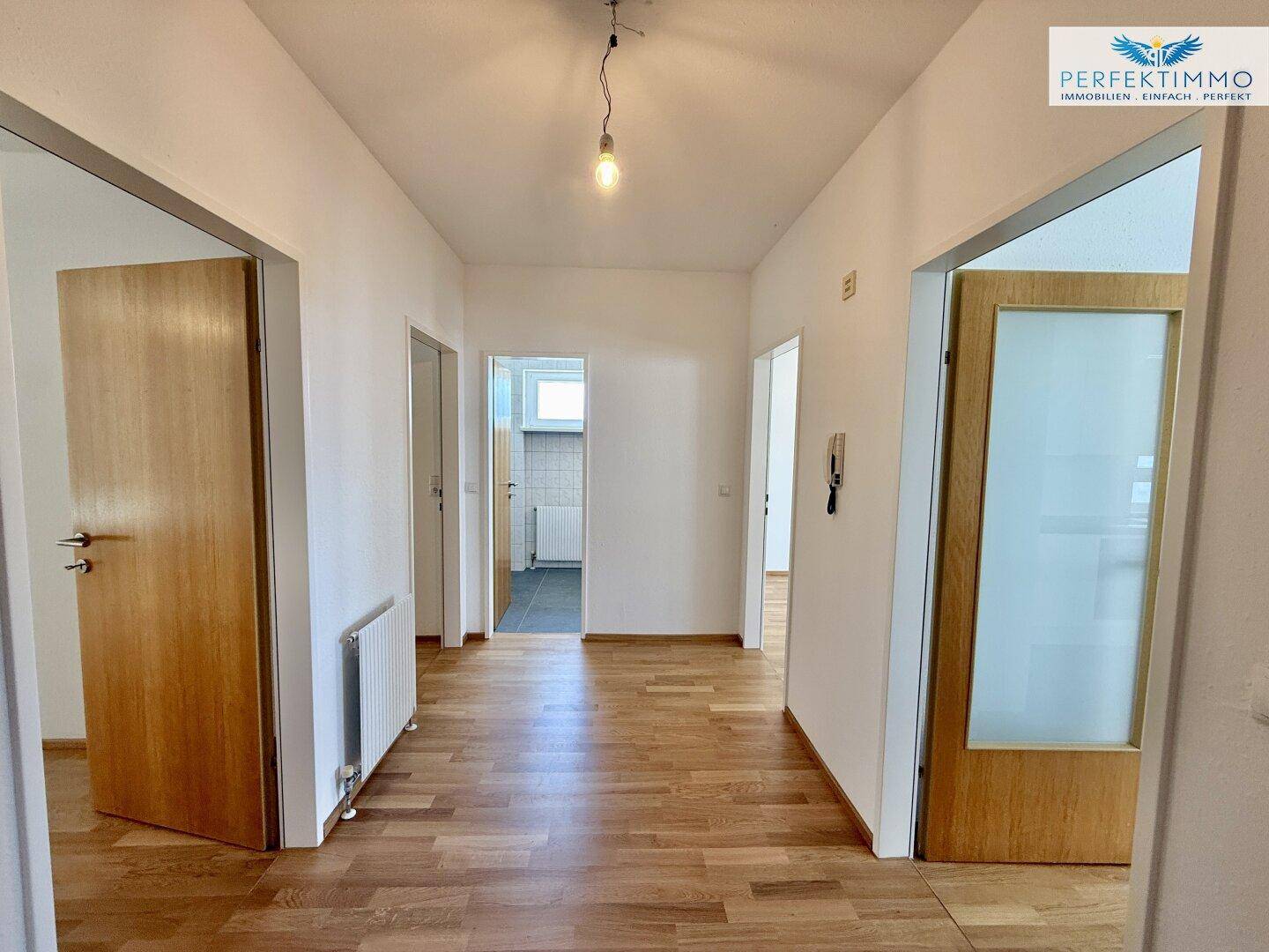 Heller Flur mit Parkettboden und mehreren Holztüren, der die verschiedenen Räume der Wohnung verbindet.