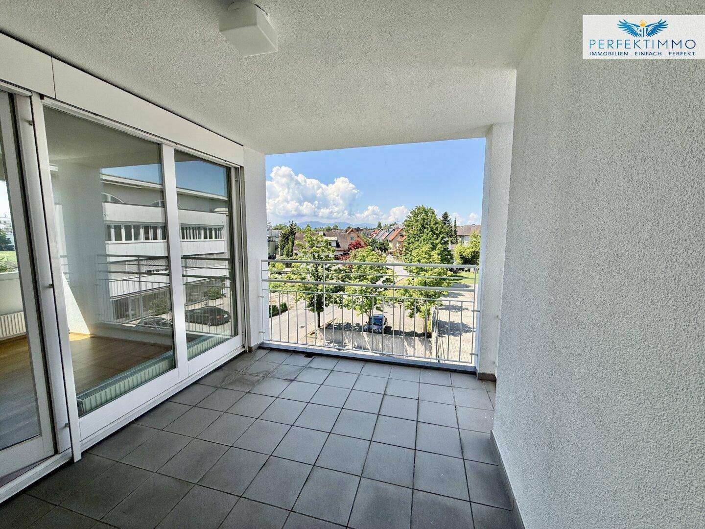 Heller Balkon mit Fliesenboden und Metallgeländer, bietet einen weiten Blick über die Umgebung.