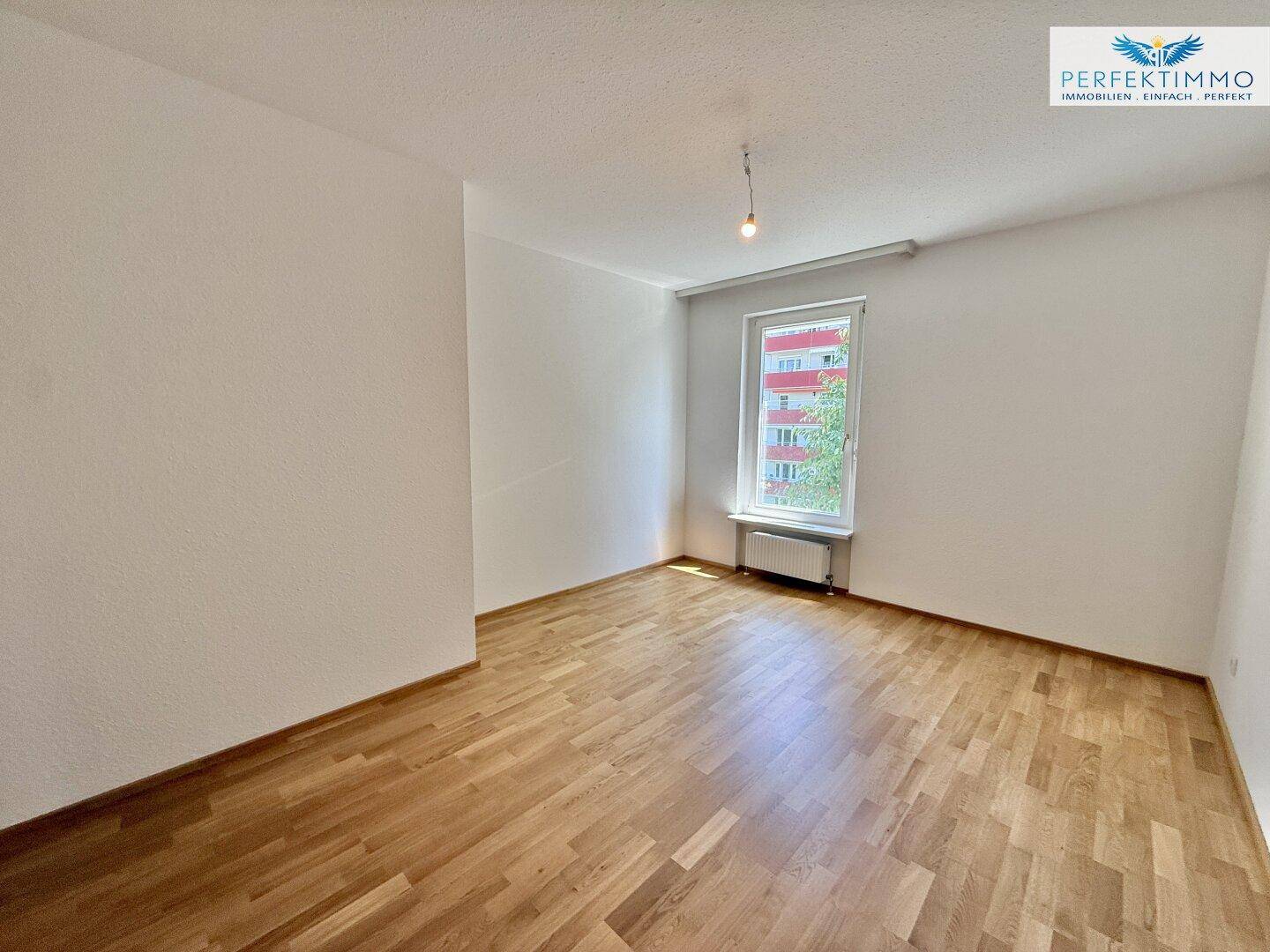 Geräumiges Schlafzimmer mit hellem Parkettboden und weißen Wänden, bereit zur individuellen Gestaltung.