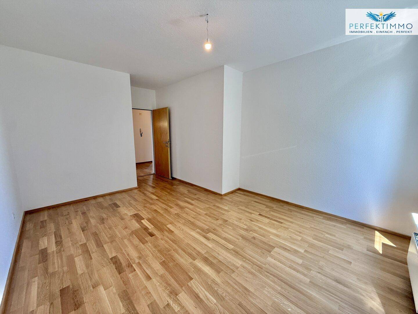 Neutral gestaltetes Schlafzimmer mit Parkettboden und Holztür, bietet vielseitige Einrichtungsmöglichkeiten.