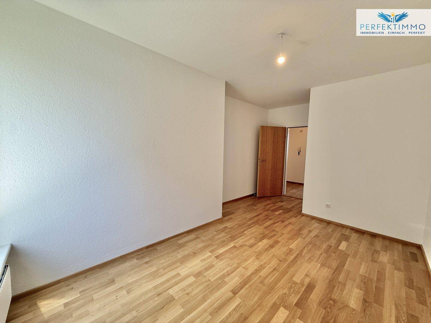 Neutrales Zimmer mit Parkettboden und weißen Wänden, bietet eine leere Leinwand für neue Bewohner.
