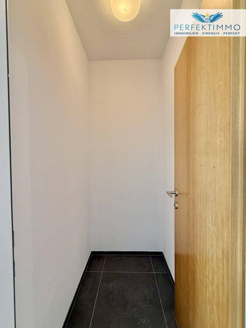Kleiner Abstellraum mit dunklem Fliesenboden und weiß gestrichenen Wänden, ideal für zusätzlichen Stauraum.
