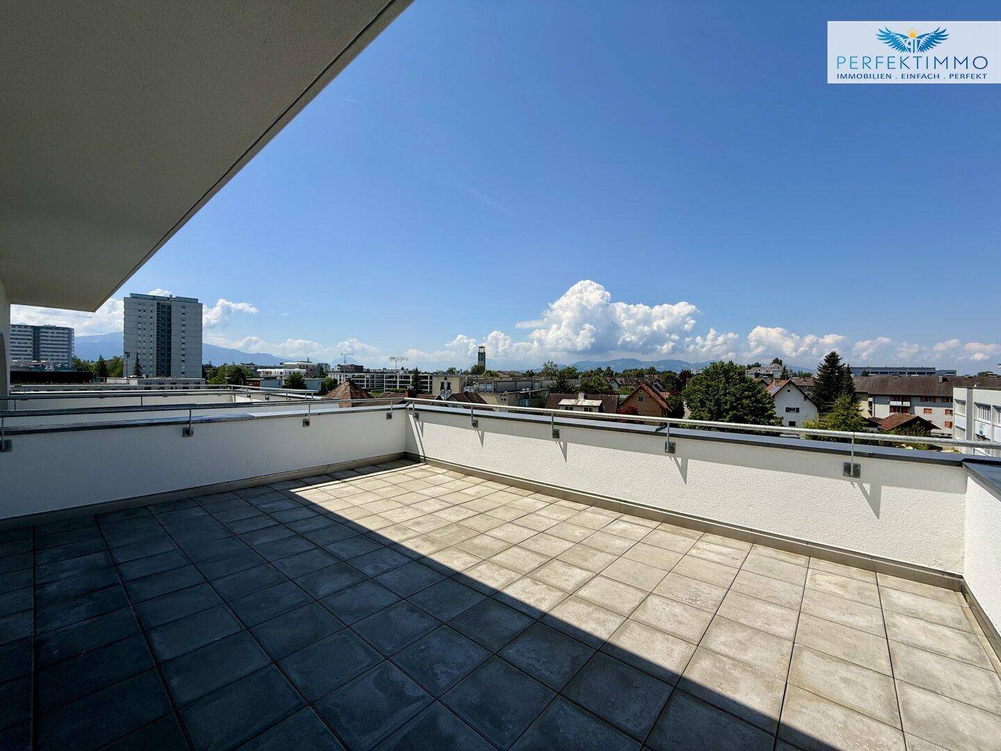 Geräumige Dachterrasse mit Fliesenboden und weitem Blick über die Stadt.