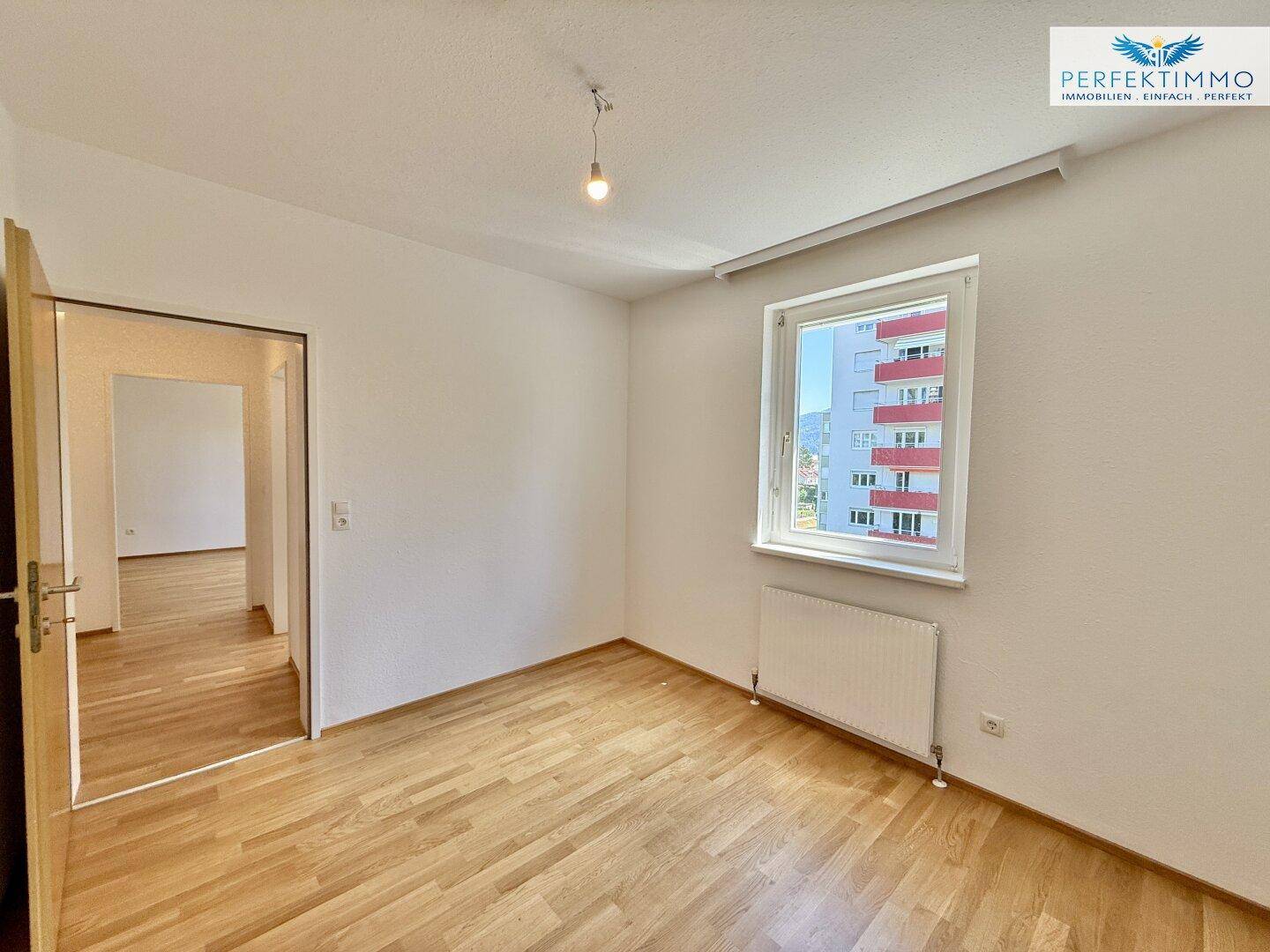 Geräumiges Schlafzimmer mit Parkettboden und Zugang zu einem weiteren Raum.