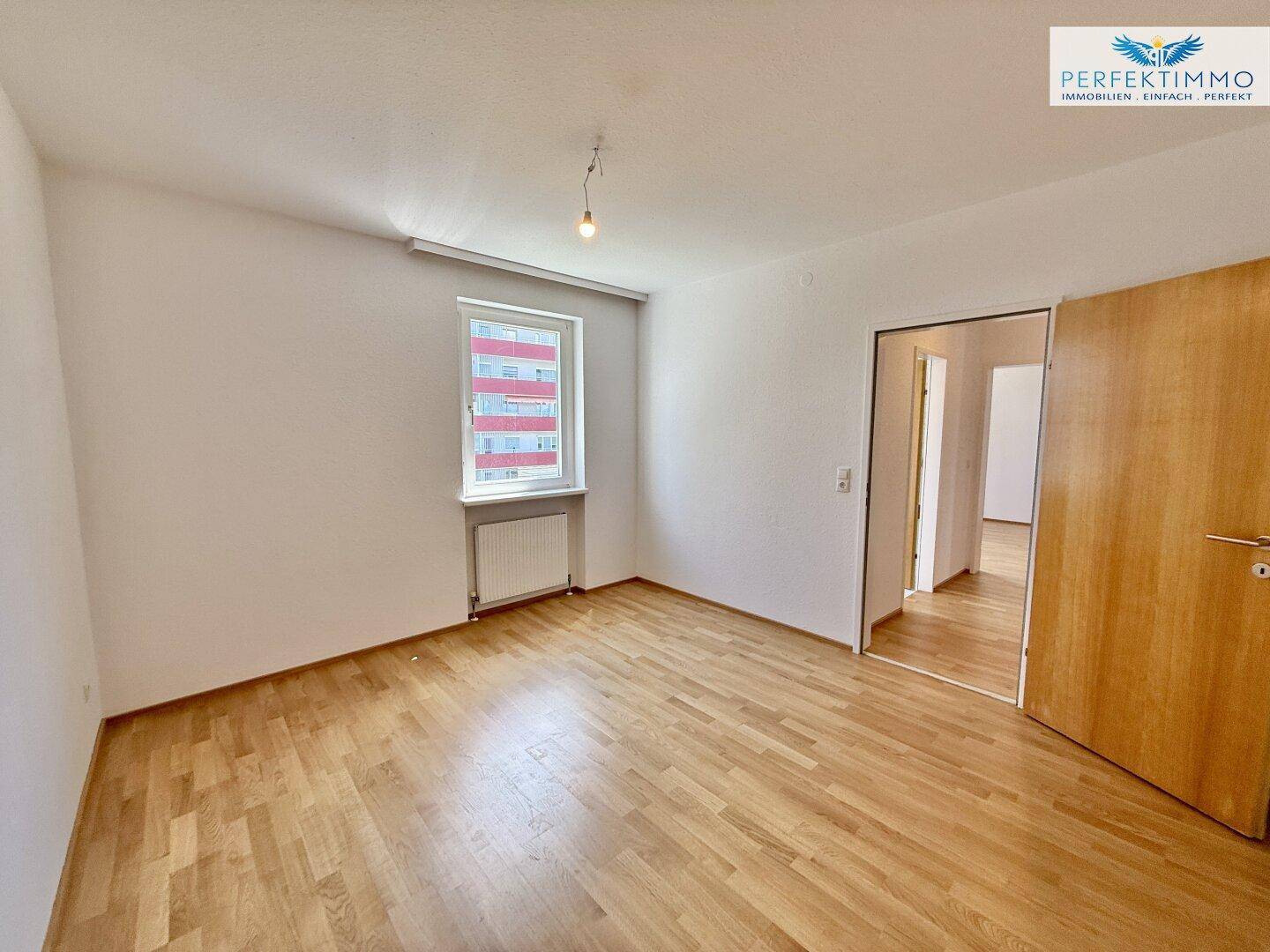 Geräumiges Schlafzimmer mit Parkettboden und Zugang zu einem weiteren Raum.