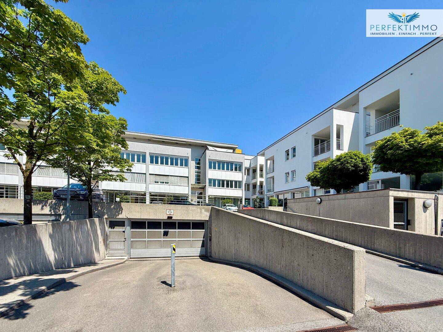 Gebäudekomplex mit Zufahrt zur Tiefgarage und modernen Fassadenelementen.