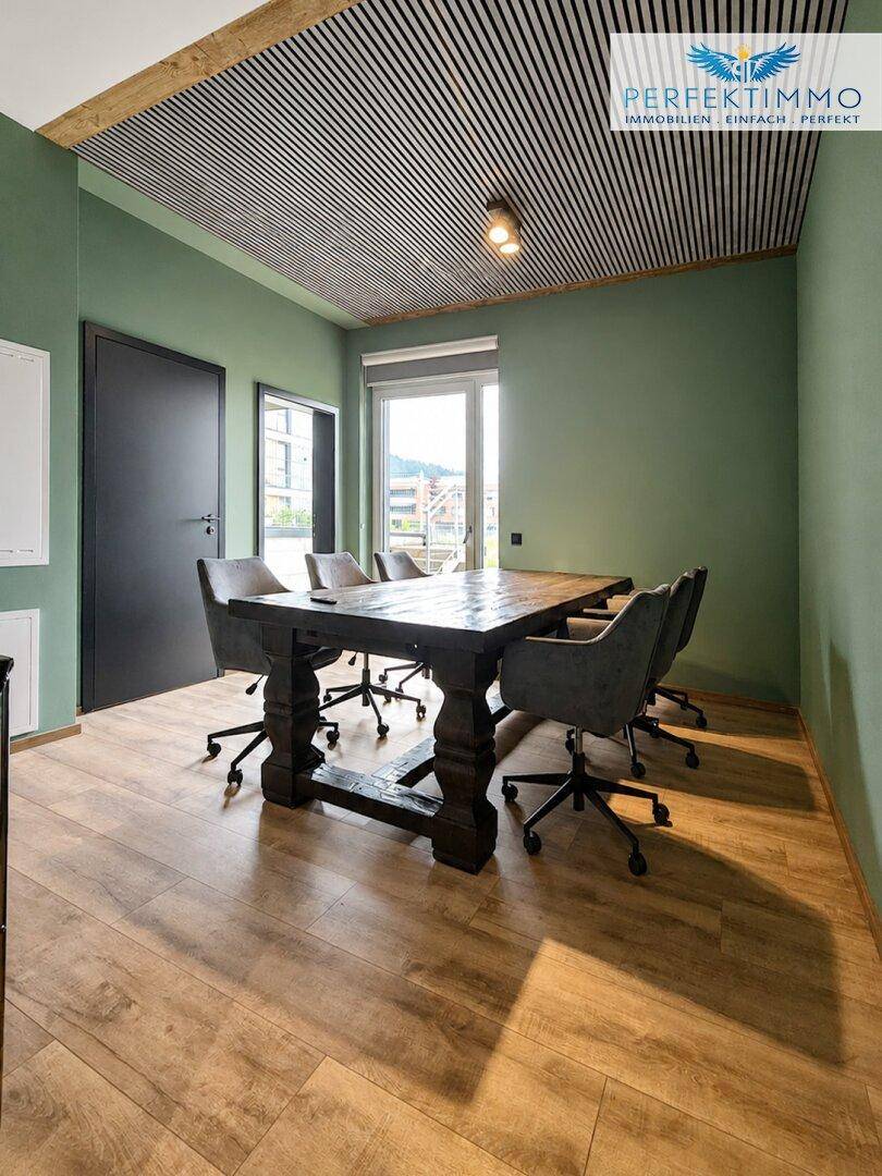 Heller Konferenzraum mit Holztisch, ergonomischen Stühlen und Blick nach draußen.