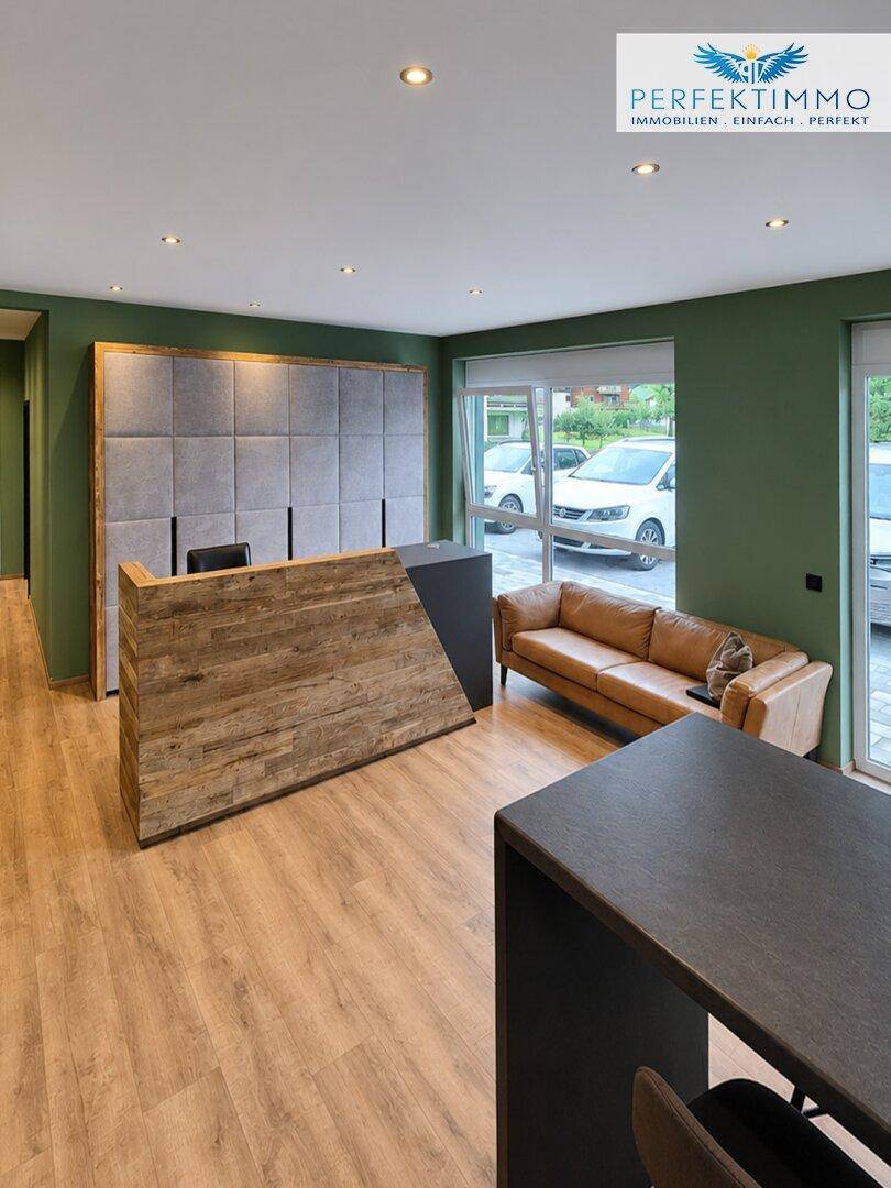 Moderner Empfangsbereich mit Holztresen, grünen Wänden und großen Fenstern.