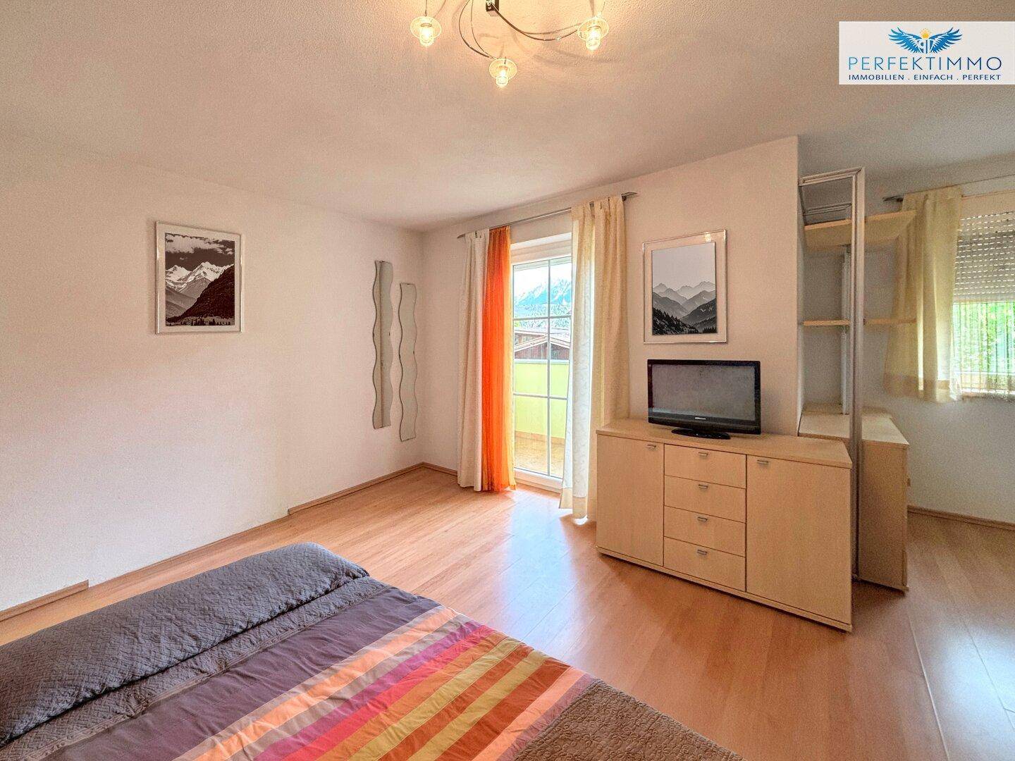 Schlafzimmer mit Holzboden, Blick auf die Berge und Zugang zu einem Balkon oder Terrasse.