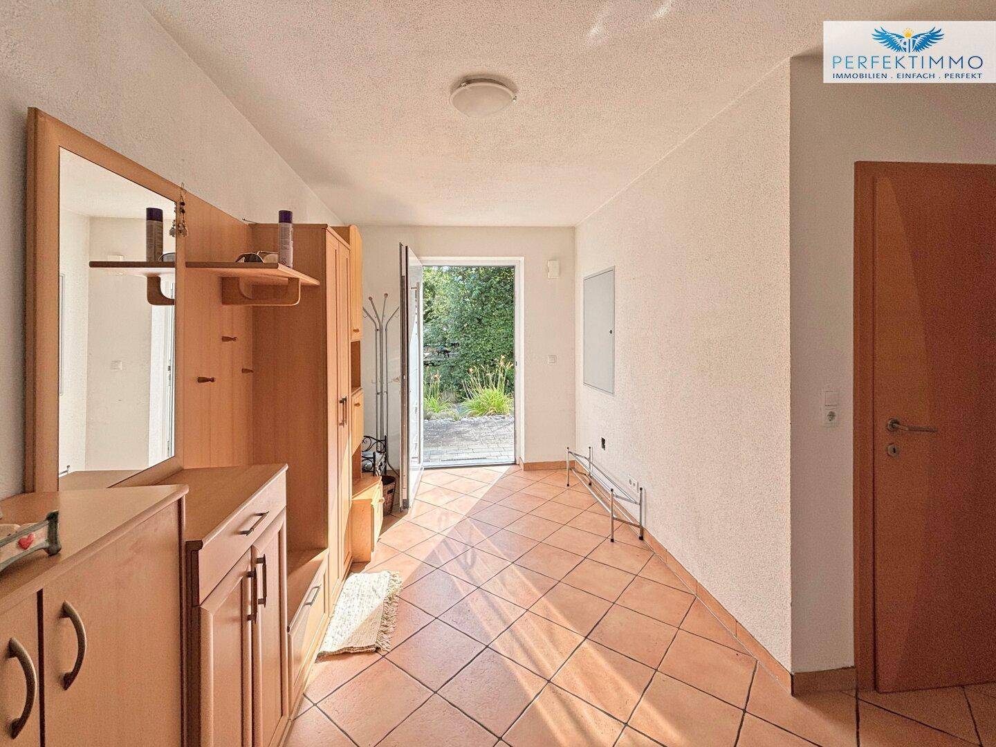 Eingangsbereich mit Terrakotta-Fliesenboden und Garderobe, hell und einladend gestaltet.