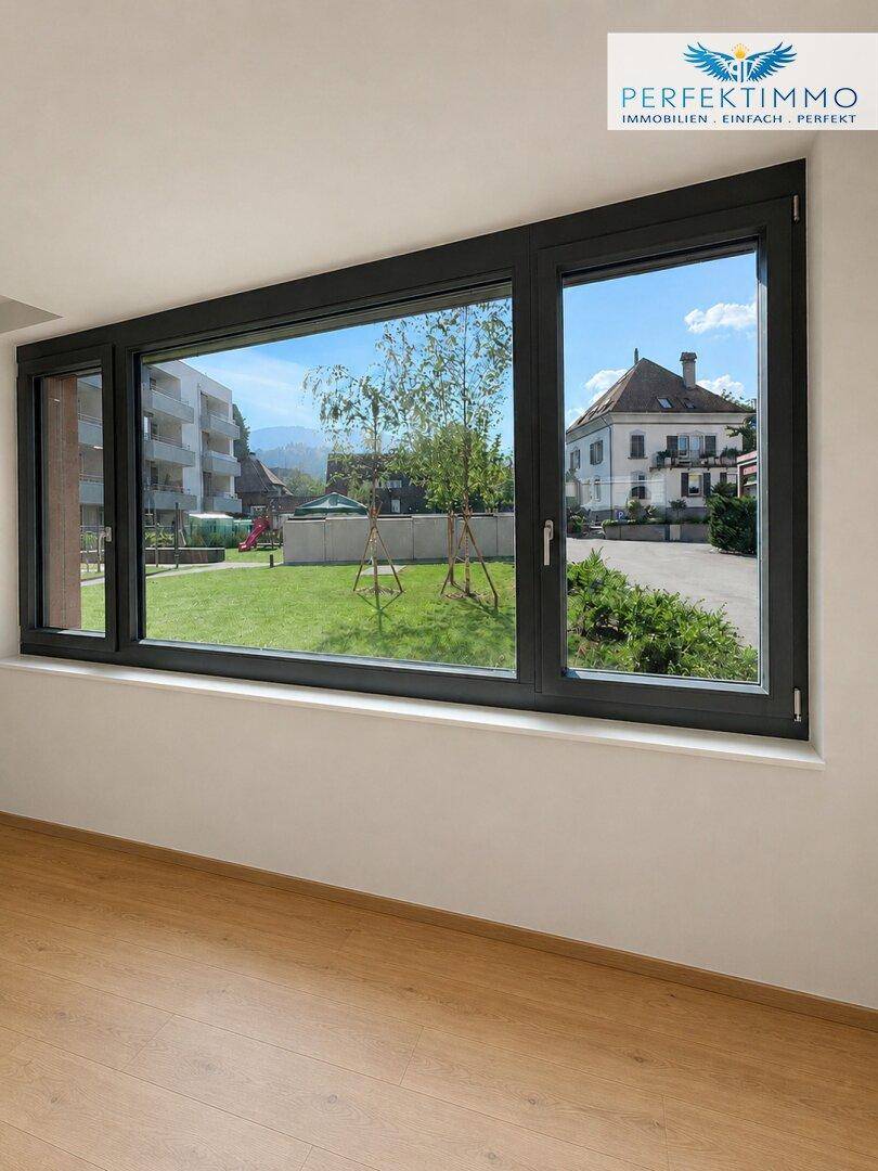 Große Fenster bieten einen schönen Blick auf einen grünen Innenhof und ein charmantes Gebäude.