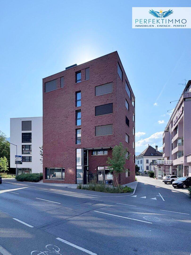 Modernes Backsteingebäude an einer Straßenecke mit großen Fenstern und zeitgenössischer Architektur.