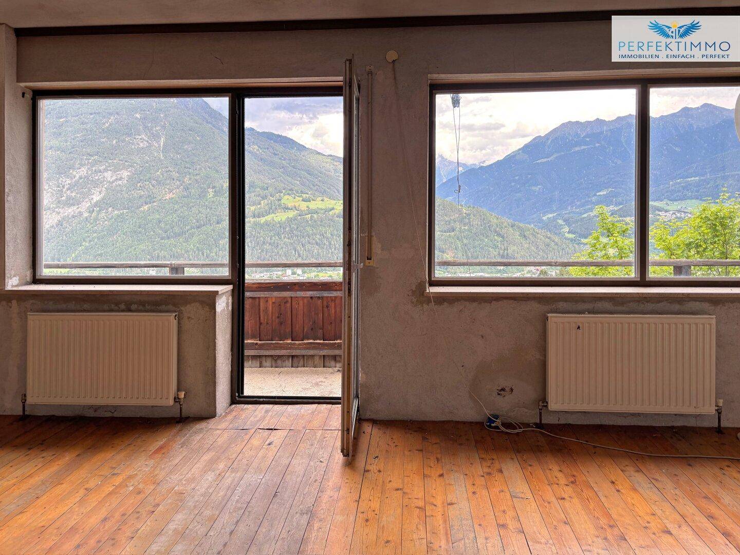 Unmöblierter Wohnraum mit Holzboden und weitem Bergblick, bereit für individuelle Gestaltung.
