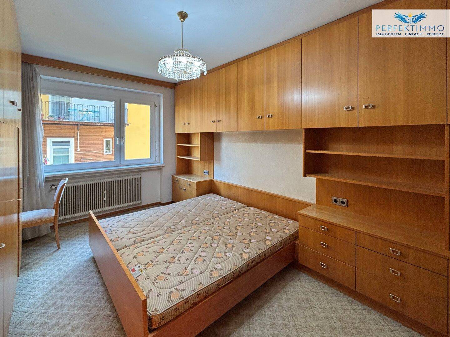 Schlafzimmer mit integrierten Holzschränken, Doppelbett und Teppichboden.