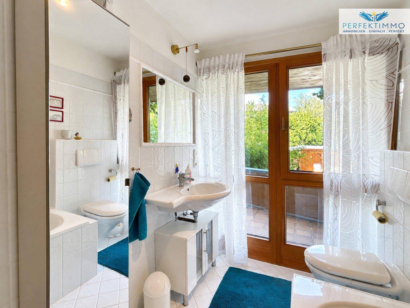 Helles Badezimmer mit weißen Fliesen, Einzelwaschbecken und Zugang zu einem Balkon.