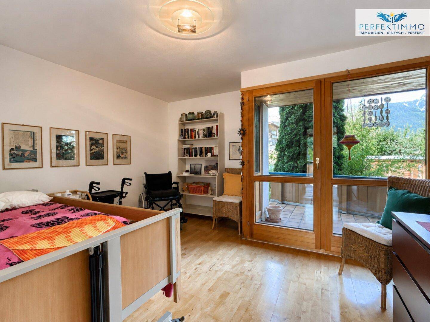 Schlafzimmer mit Holzboden, großem Fenster und Zugang zu einem Außenbereich.