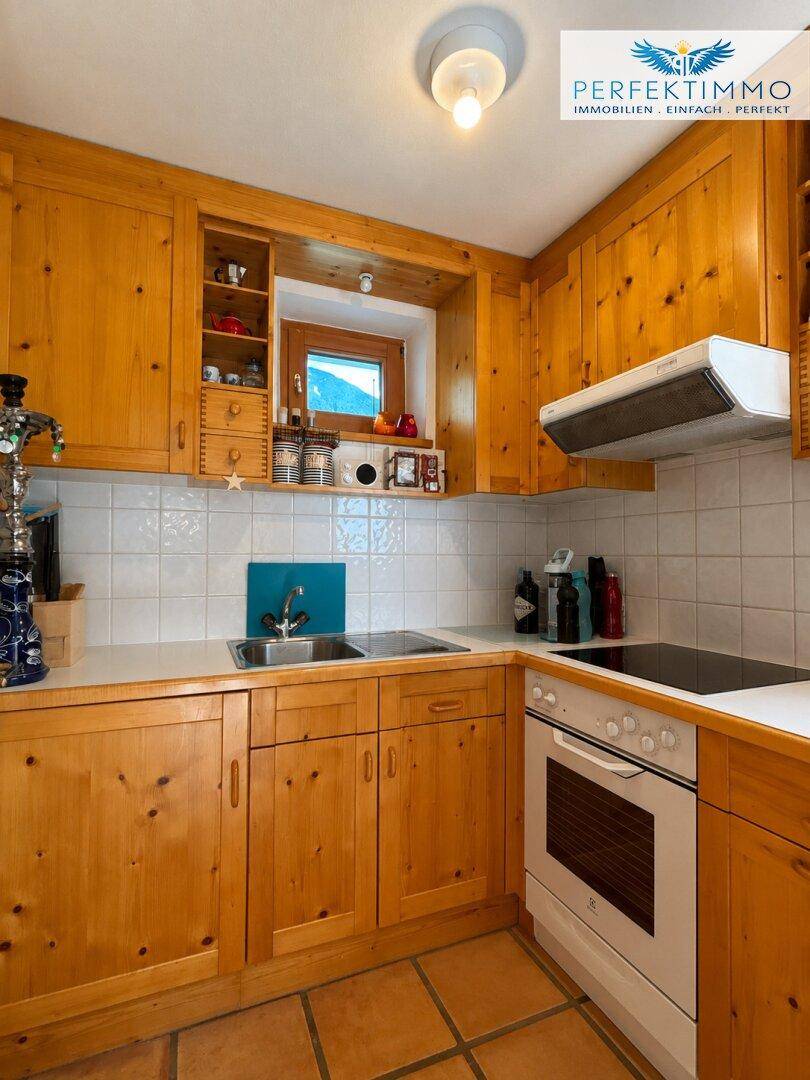 Traditionelle Holzküche mit weißen Fliesen, Einbaugeräten und einem kleinen Fenster.