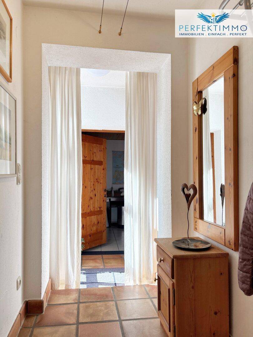 Gemütlicher Flur mit Terrakottafliesen, Holzmöbeln und einem Spiegel an der Wand.
