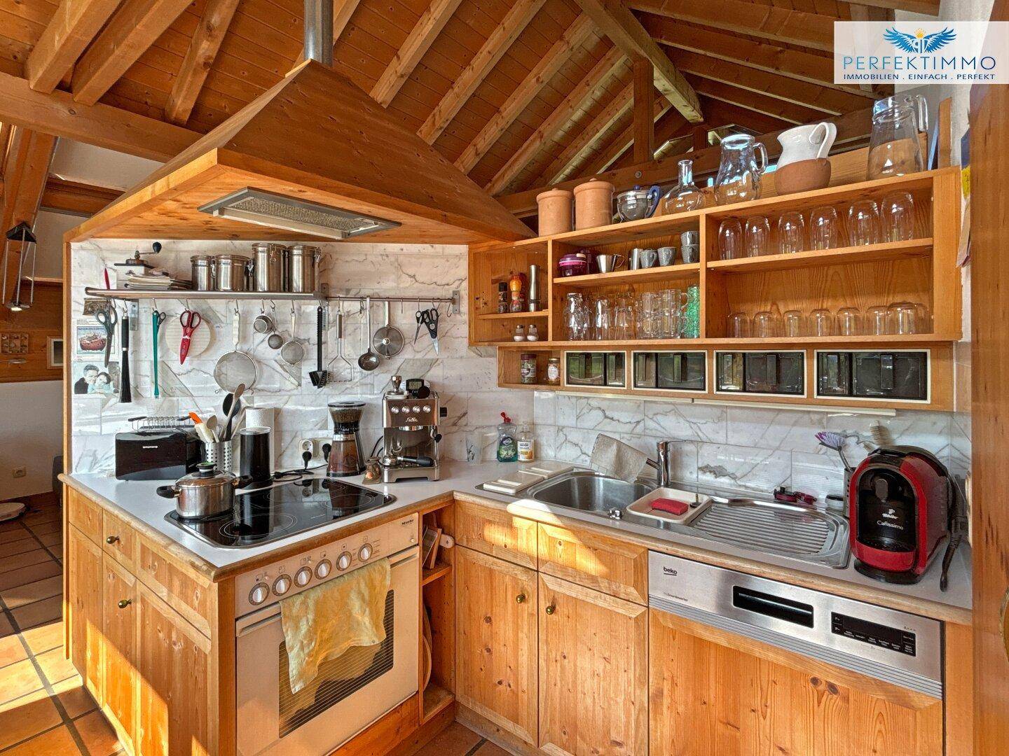 Funktionale Holzküche mit integriertem Backofen, Spülmaschine und offenem Regal unter Holzbalkendecke.