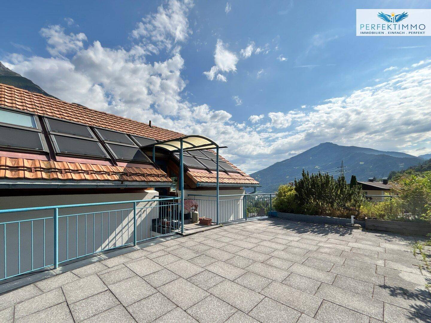 Große Dachterrasse mit Fliesenboden und weitem Blick auf die umliegende Berglandschaft.