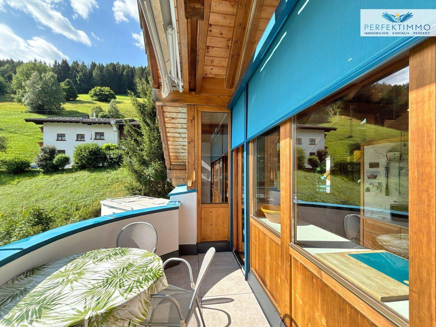 Gemütlicher Balkon mit Sitzgelegenheiten und Blick auf die grüne Umgebung und Berge.