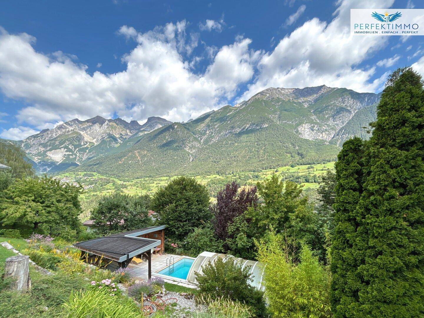 Weitläufiger Garten mit Pool, Gartenhaus und beeindruckendem Bergblick im Hintergrund.