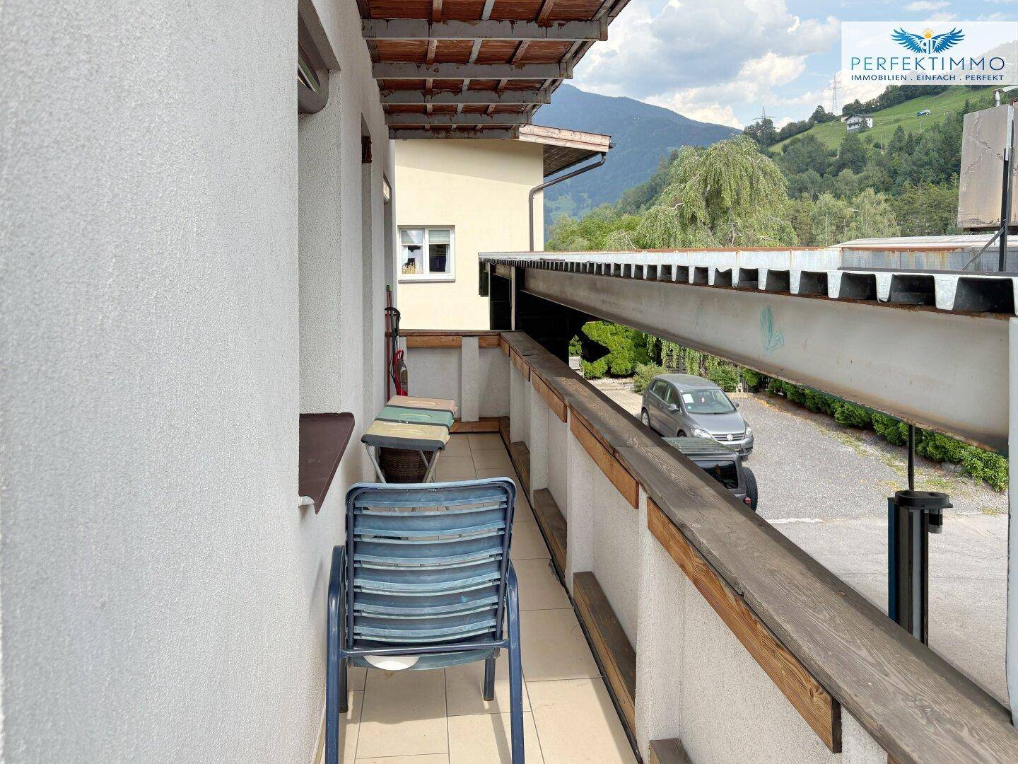 Langer Balkon mit Sitzgelegenheit und Blick auf die Umgebung und Berge.