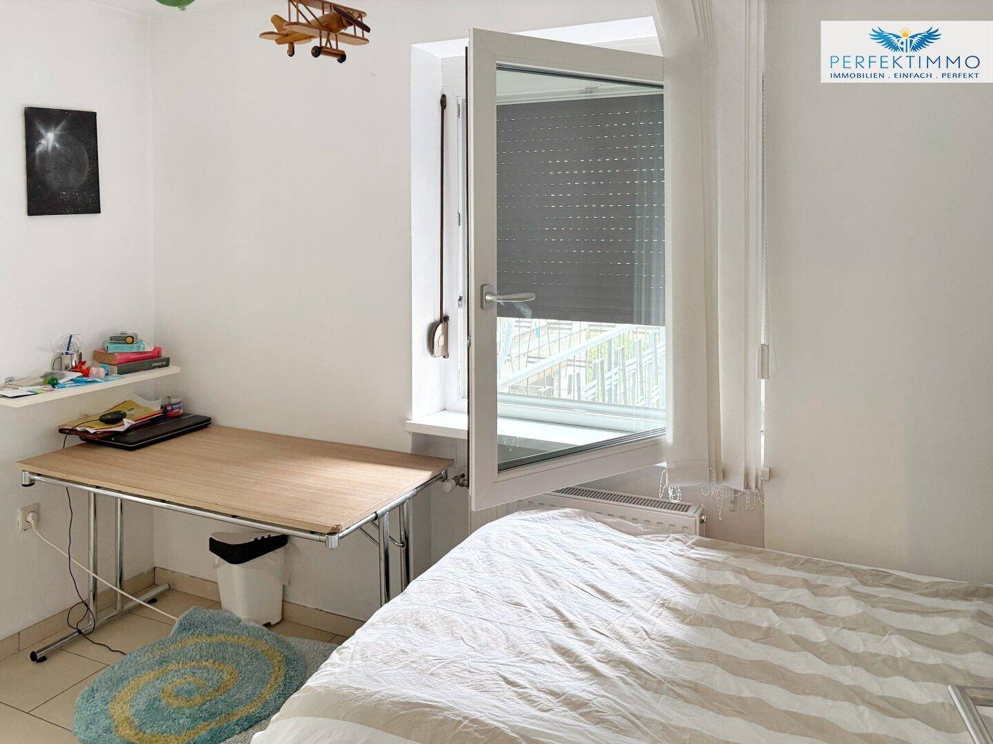 Kinderzimmer mit Einzelbett, Schreibtisch und Fenster mit Rollladen.