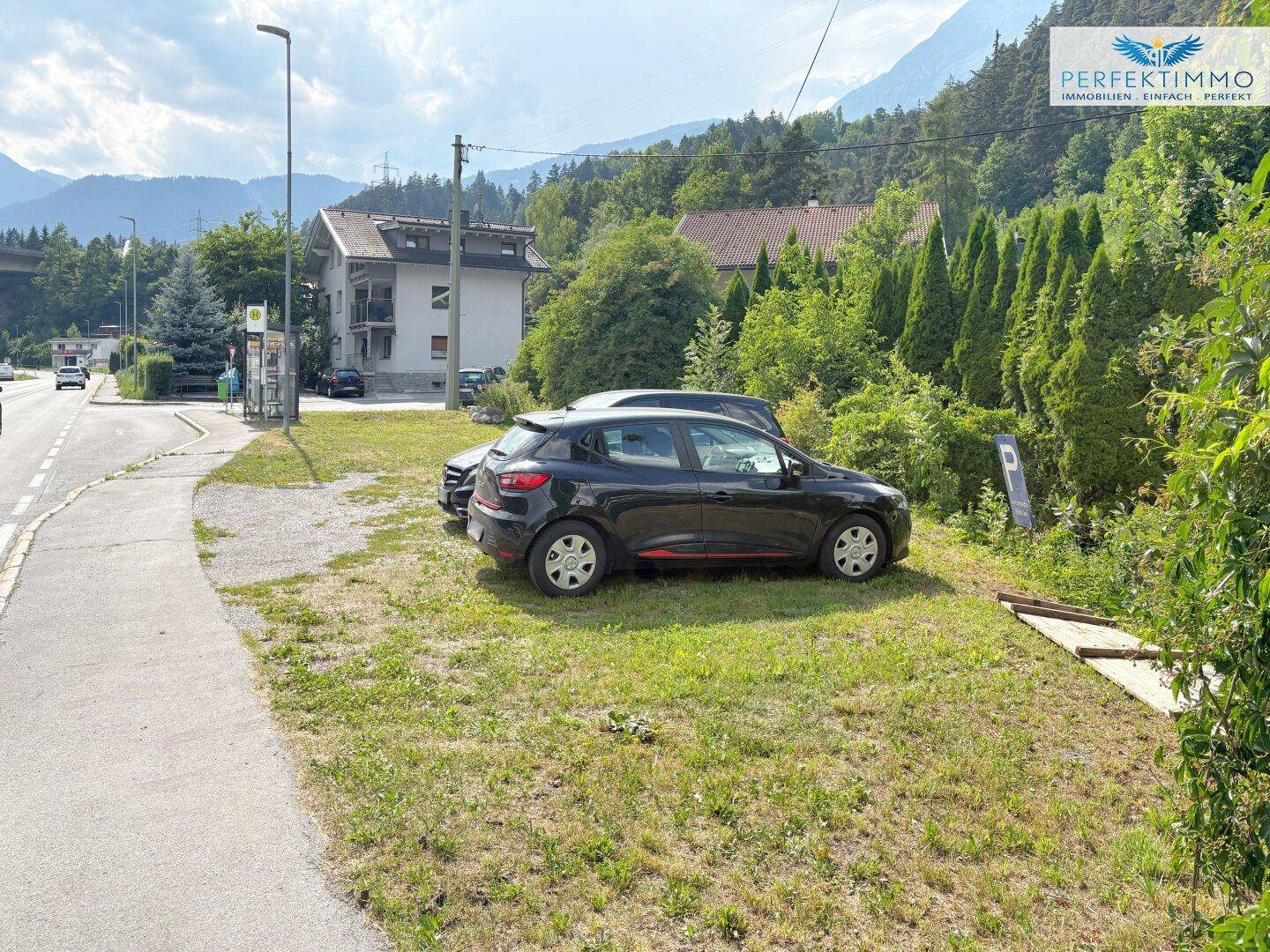 Außenbereich mit Parkplätzen und Blick auf die umliegende Berglandschaft und grüne Natur.