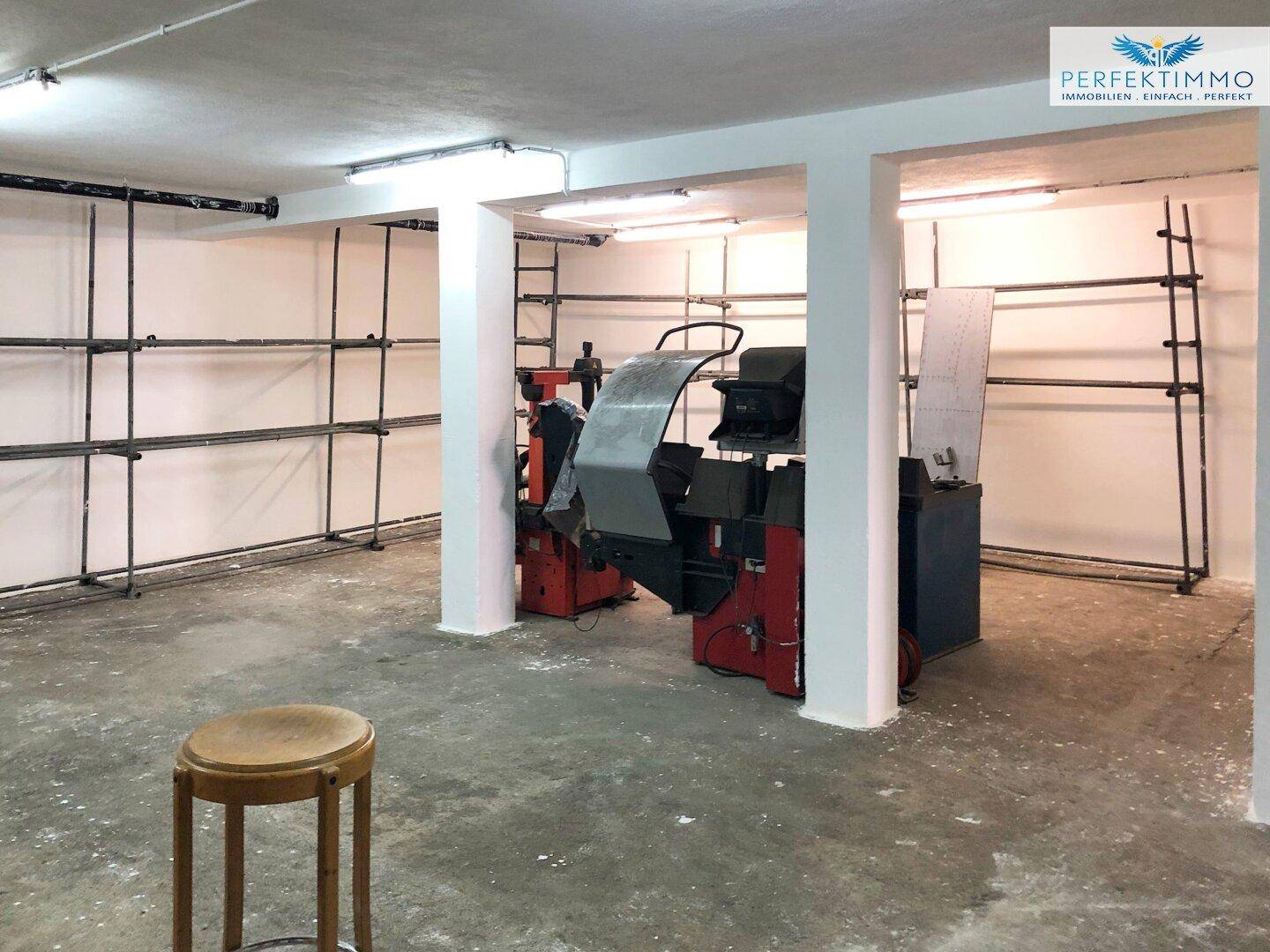 Geräumiger Werkstattbereich mit Maschinen, Regalen und Betonboden, ideal für technische Arbeiten.