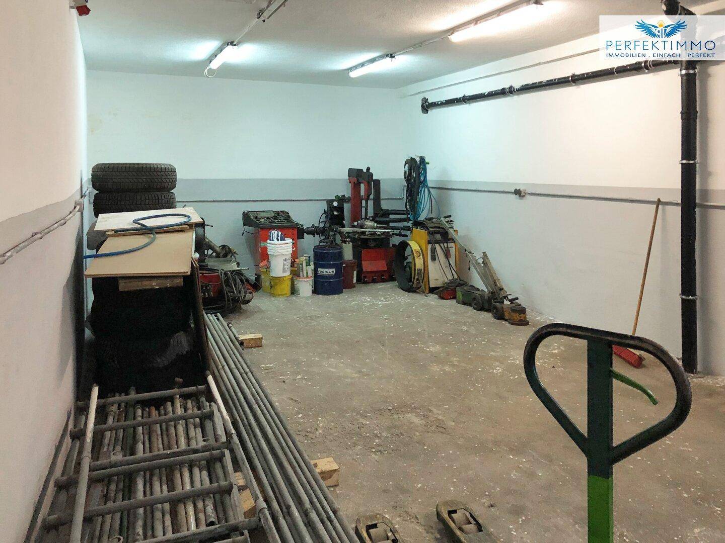 Gut ausgestatteter Werkstattraum mit Reifen, Werkzeugen und Betonboden für Reparaturen.