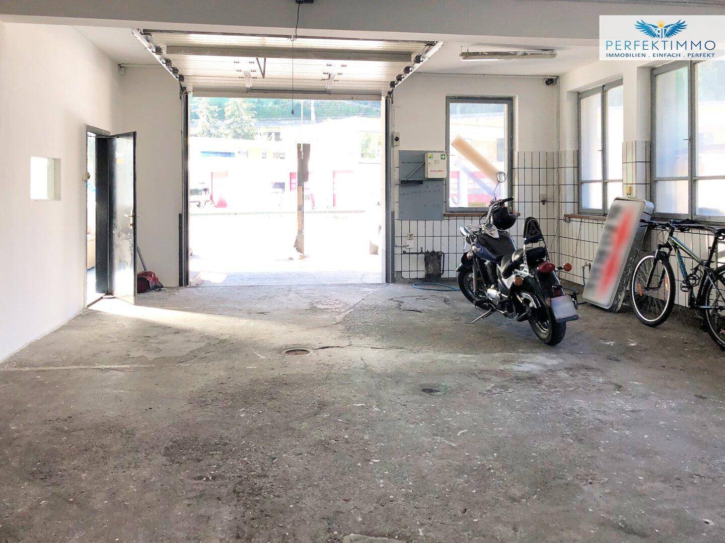 Geräumige Garage mit offenem Tor, Motorrad und Fahrrädern, bietet viel Platz.