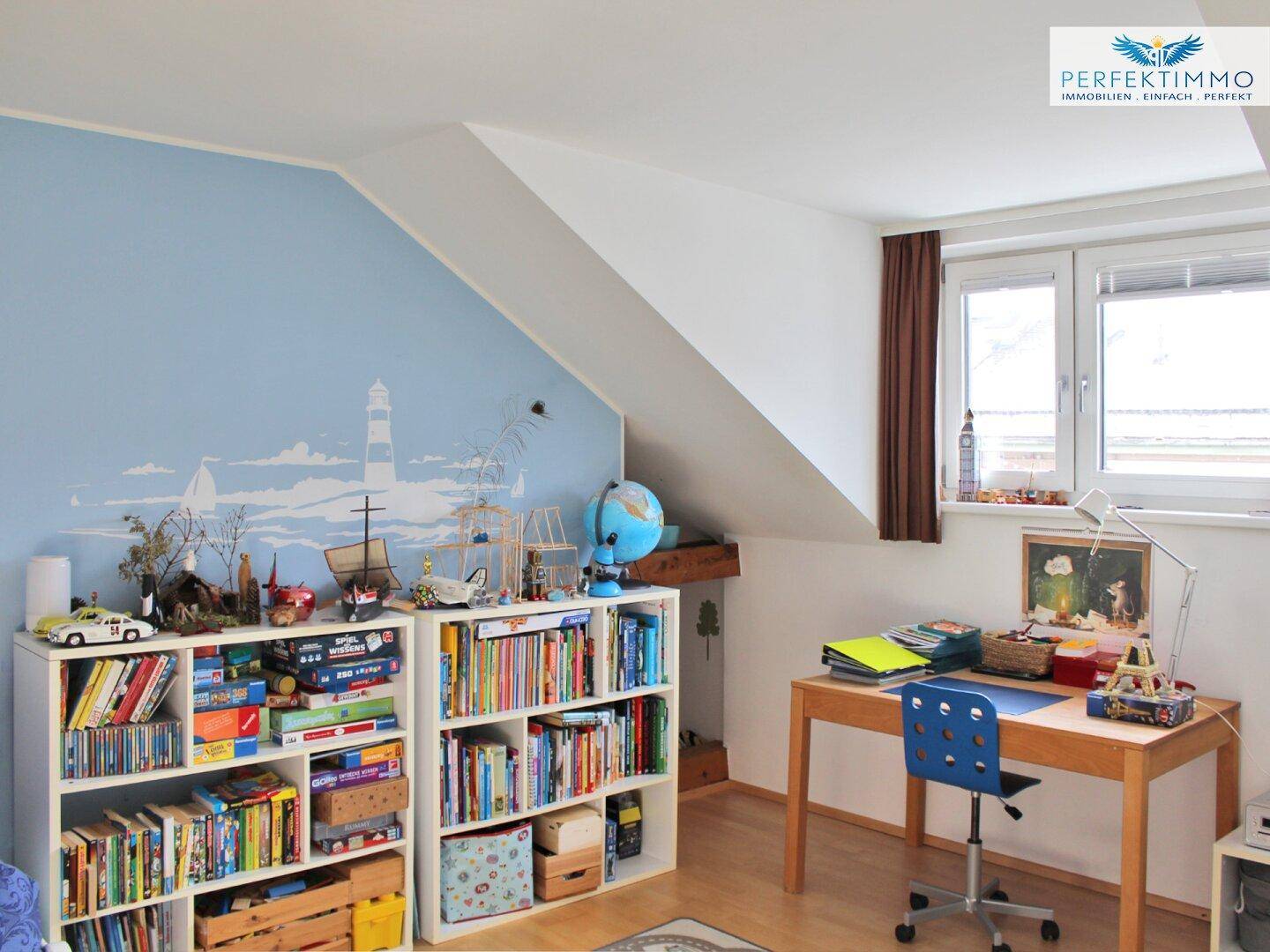 Kinderzimmer im Dachgeschoss mit farbenfroher Wandmalerei, Bücherregalen und Schreibtisch.