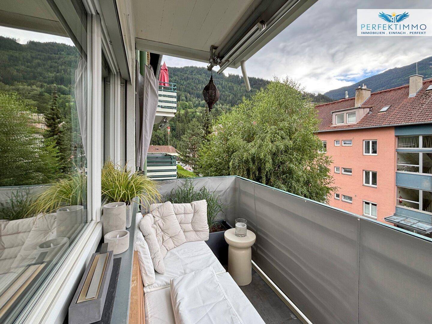Möblierter Balkon mit Bergblick und gemütlicher Sitzecke für entspannte Stunden im Freien.